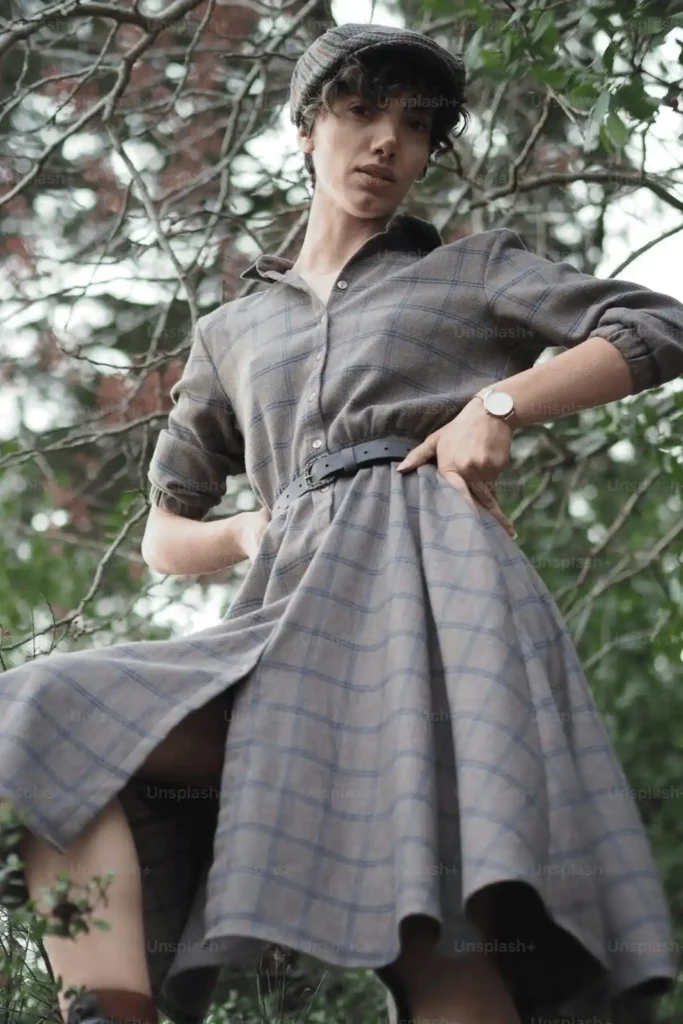 Outdoor fashion with a woman in a checkered dress and cap, exuding confidence.