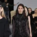 Model walking runway in sequined black dress at fashion show