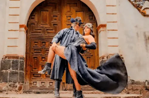 Steampunk couple embracing in front of a vintage door, showcasing dramatic fashion and accessories.