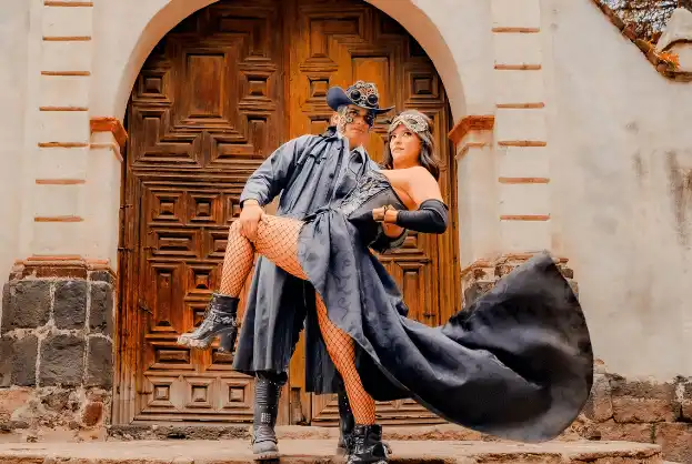 Steampunk couple embracing in front of a vintage door, showcasing dramatic fashion and accessories.