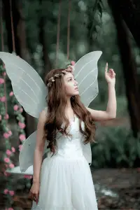Fairycore aesthetic: woman with wings and flower crown in nature.