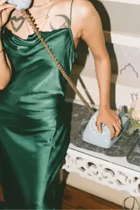 Femme fatale in a satin green dress holding a retro telephone.