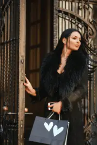 Model in luxurious fur coat holding a designer shopping bag, exuding elegance