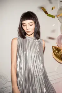 Fashion-forward model in a metallic silver inverted pleat dress with modern styling