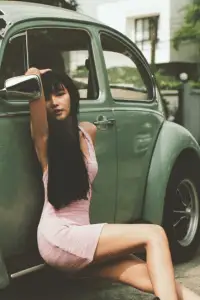 Chic vintage aesthetic captured with a model in pink and a classic car backdrop