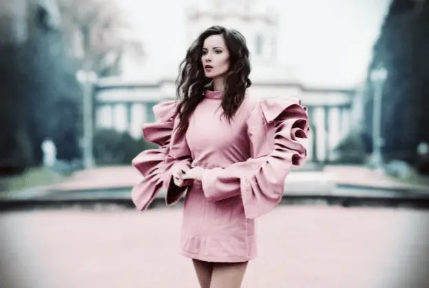 Woman in pink oversized blazer and matching dress posing on urban street