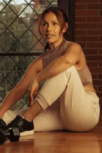 Sporty aesthetic: woman in a cropped top and joggers, stretching in a fitness studio