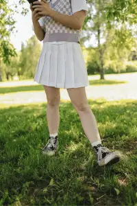Sporty yet chic look with a pleated skirt and sneakers on a sunny day