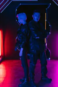 Couple in futuristic techwear standing back to back with neon accents.