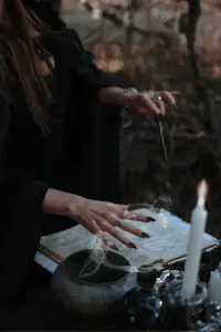 Witch performing a spell with an ancient book and candlelight.